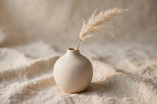 Minimalist ceramic vase with dried pampas grass on textured linen surface