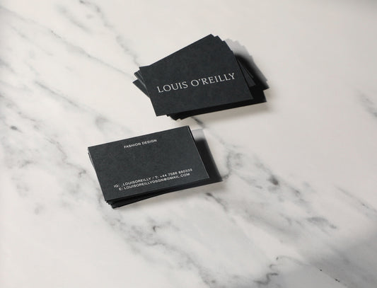 A pair of business cards sitting on top of a marble counter